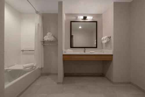 a bathroom with a sink and a mirror and a tub at Fairfield by Marriott Inn & Suites Denver Airport at Gateway Park in Denver