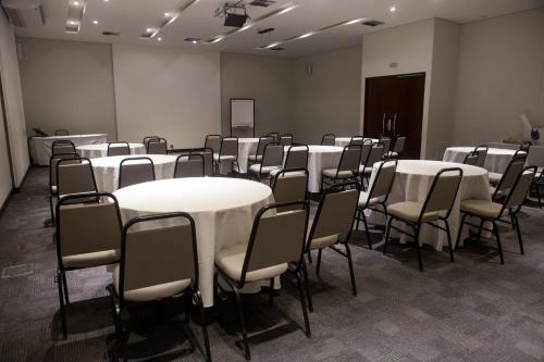 a room with white tables and chairs in it at Nobile Suítes Uberlândia in Uberlândia