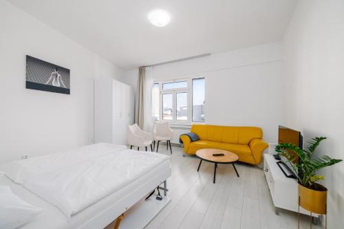 Habitación blanca con cama y sofá amarillo en Self check-in apartments by Amber, en Bratislava