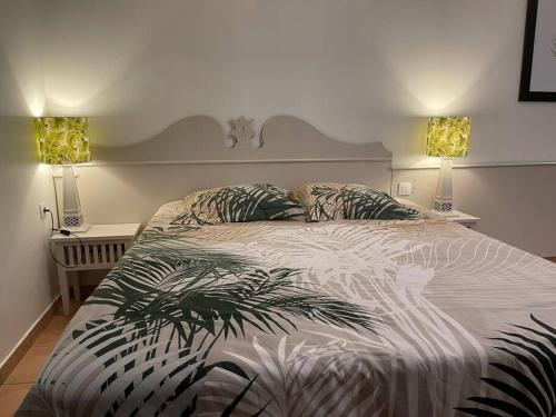 - une chambre avec un grand lit et deux lampes dans l'établissement Le Laïlana, à Sainte-Anne
