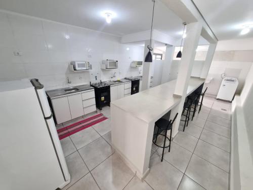 a large white kitchen with a counter and stools at Studio GT in São Carlos