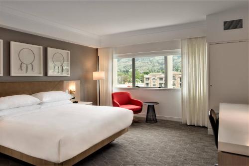 カムループスにあるDelta Hotels by Marriott Kamloopsのベッドと赤い椅子が備わるホテルルームです。