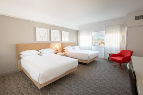 a hotel room with two beds and a red chair at Delta Hotels by Marriott Kamloops in Kamloops