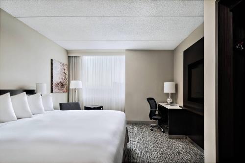 a hotel room with a large white bed and a desk at Pittsburgh Marriott North in Cranberry Township