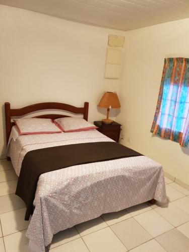 ein Schlafzimmer mit einem Bett und einem Tisch mit einer Lampe in der Unterkunft RESIDENCE VERO in Matoury