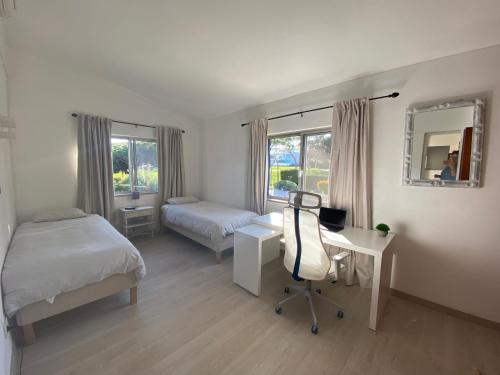 韋爾都勒博的住宿－Royal Course Villa, Vale do Lobo，一间卧室配有两张床、一张桌子和一张书桌