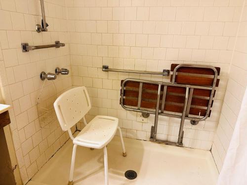 a bathroom with a toilet and a chair in it at Rodeway Inn Winslow I-40 in Winslow