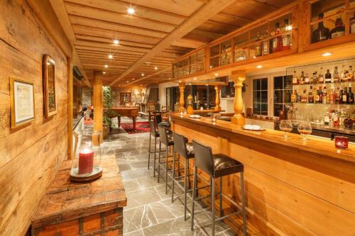 a bar with stools in a room with wooden walls at Griesalp Hotels in Kiental