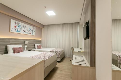 a hotel room with two beds and a television at IT Itabira Hotel in Itabira
