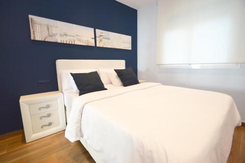 um quarto com uma cama branca e uma parede azul em Fuengirola, Primera linea de playa em Fuengirola