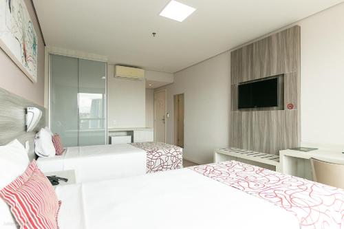 a hotel room with two beds and a flat screen tv at IT Itabira Hotel in Itabira