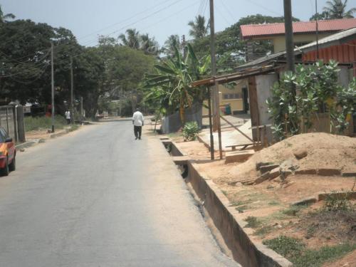 a man walking down a street next to a house at Marrets International Hotel - "Express" in Cape Coast