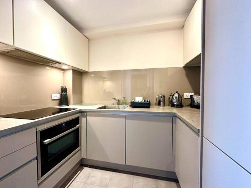 a kitchen with white cabinets and a sink at Beautiful Couples Retreat - FREE Parking & WiFi - 1 Minute walk to Poole Quay - Great Location - Free Parking - Fast WiFi - Smart TV - Newly decorated - sleeps up to 2! Close to Poole & Bournemouth & Sandbanks in Poole