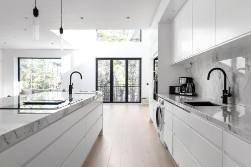 a white kitchen with white counters and appliances at Stylish and spacious family home in Stockholm