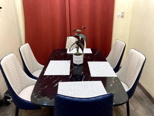 einem schwarzen Tisch mit weißen Stühlen und einer Topfpflanze in der Unterkunft Superbe mini-villa tout confort! in Ouagadougou
