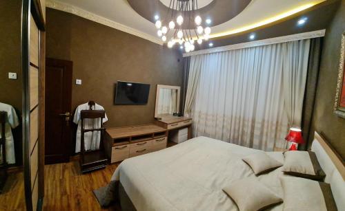 a bedroom with a bed and a television and a chandelier at LUXURIOUS ACCOMMODATION IN 2BR APARTMENT, IN A SECURED AREA WITH COMFORTABLE DISTANCE TO R/W STATION, AIRPORT AND CITY CENTER. in Tashkent