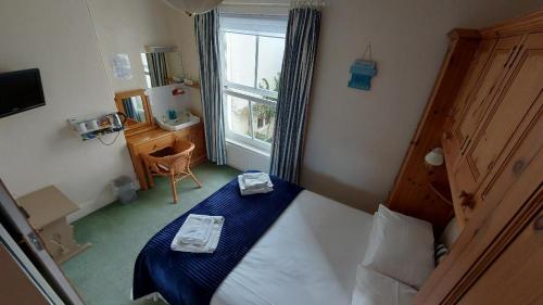 een slaapkamer met een bed met blauwe lakens en een raam bij The Clifton at Paignton in Paignton