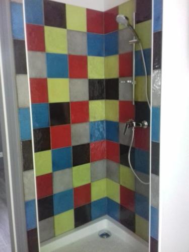 La salle de bains est pourvue d'une douche et d'un mur en carrelage coloré. dans l'établissement Gîte mosaïque Accueil rando, pêche, farniente, à Latouille-Lentillac