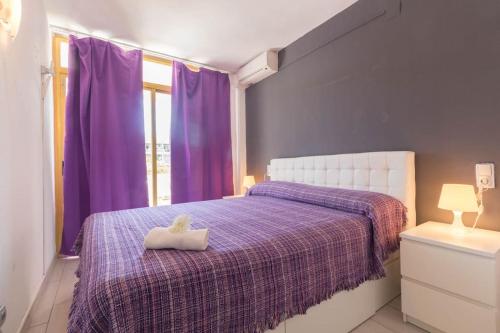 ein Schlafzimmer mit violetten Vorhängen und einem Bett mit ausgestopftem Tier darauf in der Unterkunft Complejo Residencial-CAT-8 in Salou