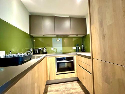 a kitchen with wooden cabinets and green walls at Chic Modern Apartment Suite - Free Parking & WiFi! - 1 Minute walk to Poole Quay - Great Location - Free Parking - Fast WiFi - Smart TV - Newly decorated - sleeps up to 2! Close to Poole & Bournemouth & Sandbanks in Poole