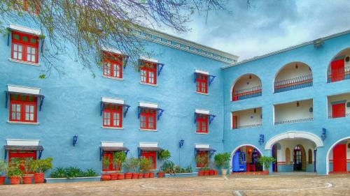 un edificio azul con ventanas rojas y un árbol en HOTEL COLONIAL MATAMOROS, en Matamoros