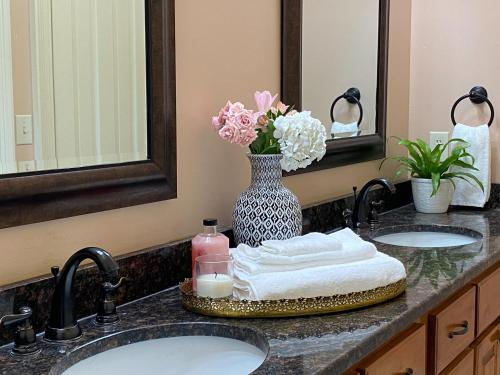 a bathroom counter with two sinks and a vase of flowers at Downtown Mobile, AL 2 Bedroom Townhome - Walk to Everything! in Mobile