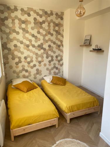 twee bedden in een kleine kamer met gele lakens bij Gîte du Damier in Saint-Valery-sur-Somme