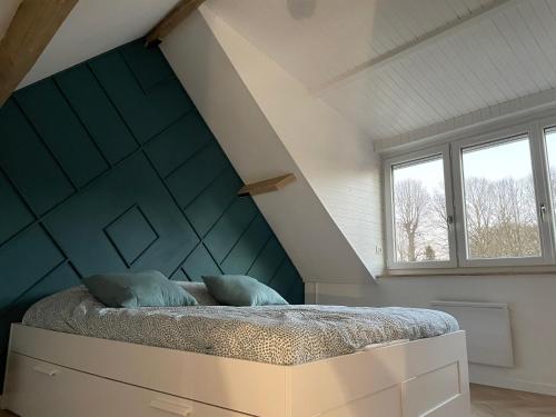 een slaapkamer met een bed met een blauwe muur bij Gîte du Damier in Saint-Valery-sur-Somme