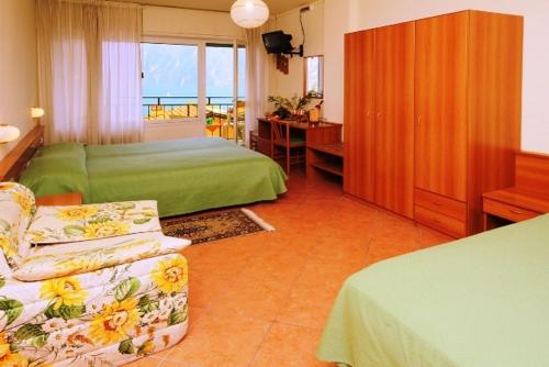 ein Schlafzimmer mit einem Bett, einem Stuhl und einem Schreibtisch in der Unterkunft Hotel Susy in Limone sul Garda