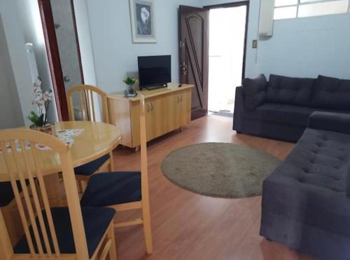 ein Wohnzimmer mit einem Tisch und einem Sofa in der Unterkunft Apartamento Central, quarto andar in Serra Negra