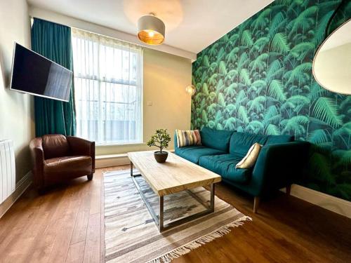 a living room with a green couch and a table at Amazing Modern Apartment - Free Secure Parking! - 1 Minute walk to Poole Quay - Great Location - Free Parking - Fast WiFi - Smart TV - Newly decorated - sleeps up to 2! Close to Poole & Bournemouth & Sandbanks in Poole