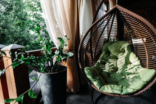 a wicker swing sitting on a balcony next to a plant at Park-Hotel Villa Vita in Kyiv