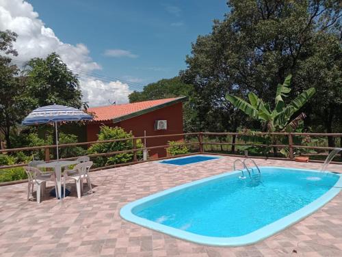 een zwembad met een tafel en stoelen en een parasol bij Pousada Sítio São Pedro in Delfinópolis