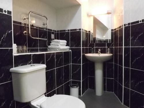 a black tiled bathroom with a toilet and a sink at Palace Hotel - Small Hotel in Oban