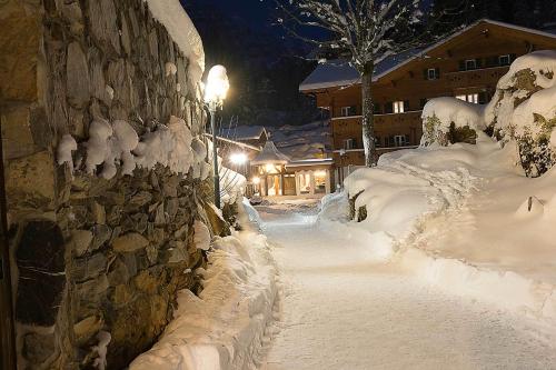 a street covered in snow next to a stone wall at Griesalp Hotels in Kiental