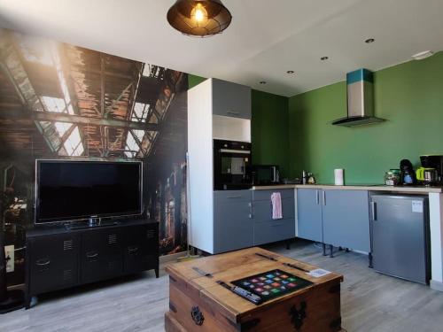 cocina con TV y mesa en una habitación en Les Studios De Flo' : The Bel'Factory 38 m² WIFI, en Belfort
