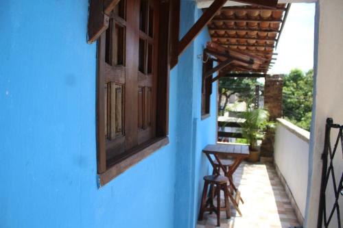 um edifício azul com uma janela e bancos num alpendre em ROSÁRIO TEMPORADA Hostel em Olinda
