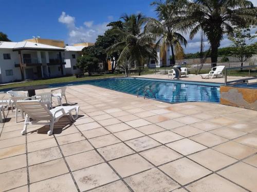 een zwembad met stoelen naast een resort bij Apartamento pé na areia in Porto Seguro