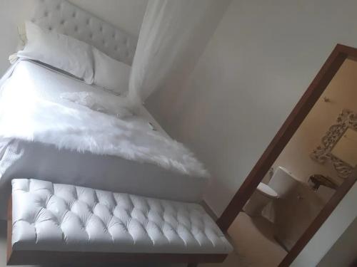 een wit bed met witte lakens en kussens bij Apartamento pé na areia in Porto Seguro