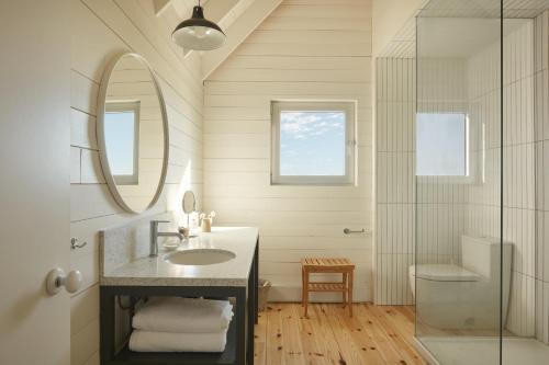 W łazience znajduje się umywalka, lustro i prysznic. w obiekcie Les Rochers - Îles de la Madeleine w mieście Havre-Aubert