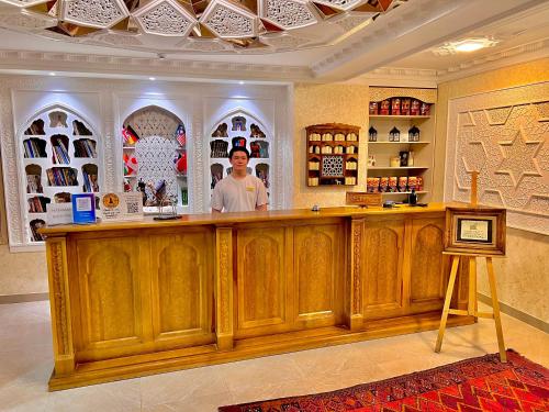 a man standing behind a wooden bar in a store at Miniature Boutique Hotel in Bukhara