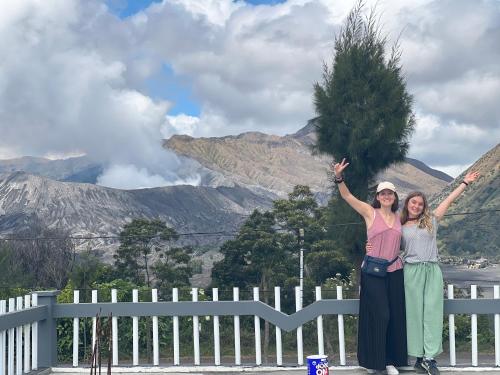 two women standing next to a fence with their hands in the air at Cahyo Homestay Bromo in Bromo