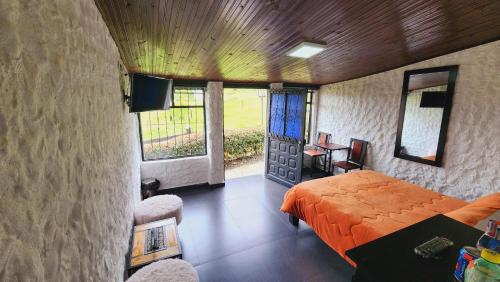 a bedroom with a bed and a desk and some windows at Hospedaje campestre los pinos in Guatavita