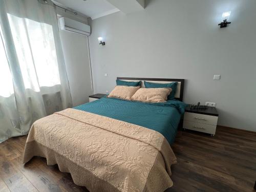 a bedroom with a bed with blue sheets and a window at English Breakfast in Chişinău