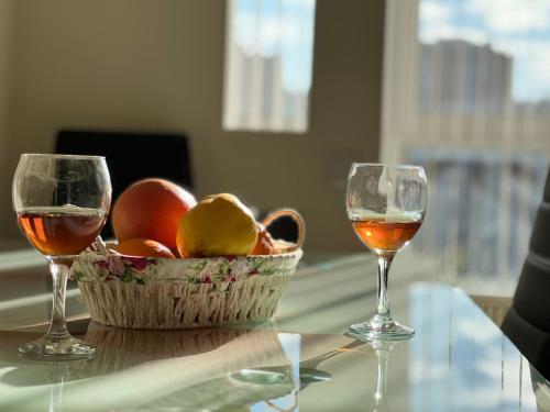 two glasses of wine and a basket of fruit on a table at English Breakfast in Chişinău