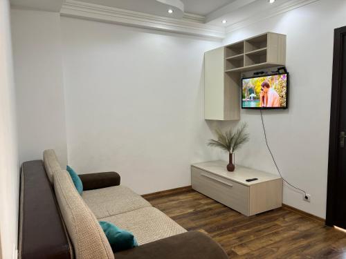 ein Wohnzimmer mit einem Sofa und einem TV an der Wand in der Unterkunft English Breakfast in Chişinău