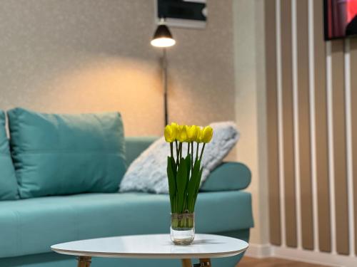 a vase of yellow flowers on a table next to a couch at Hi-tech aparts in Chişinău