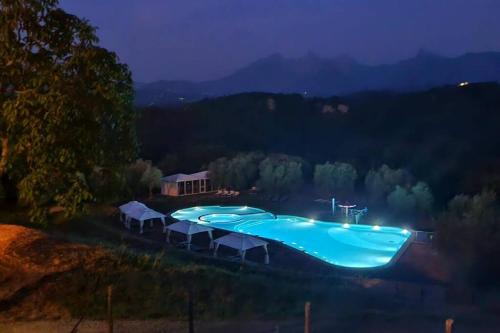 una gran piscina azul con mesas y sombrillas en Appartamento La Mimosa en Monti di Licciana Nardi