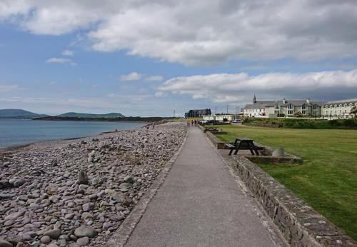 a walkway next to a beach with a bench at Waterville Holiday Homes No 10 by Trident Holiday Homes in Waterville
