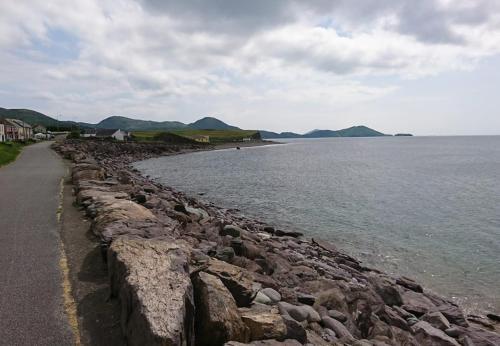 a rocky shoreline with the ocean and mountains in the background at Waterville Holiday Homes No 10 by Trident Holiday Homes in Waterville